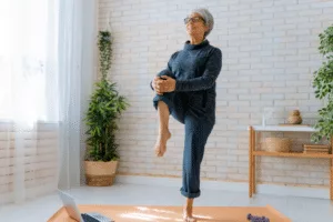 A woman doing yoga at home with a laptop.