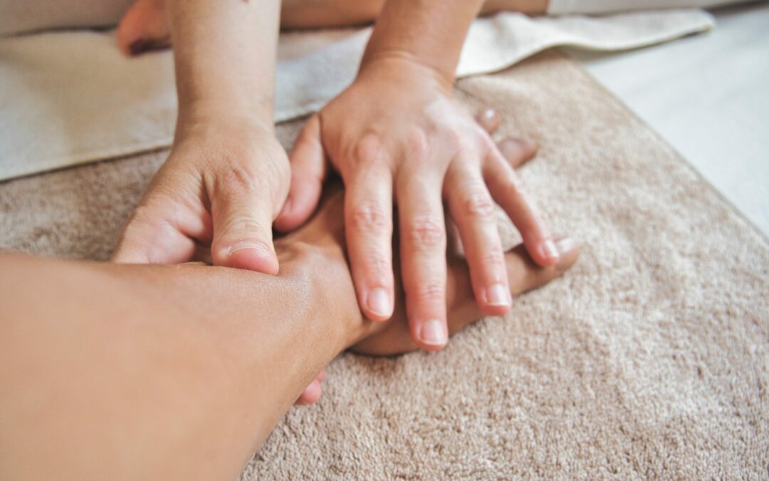 A woman receiving a Sports Massage Therapy to speed up her recovery from injuries, while lying on a towel.