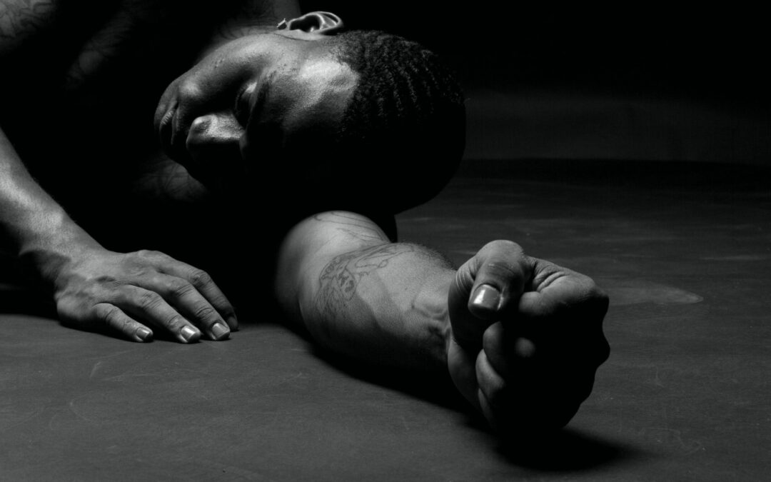 A black and white photo capturing an athlete in a moment of rest and recovery on the ground.